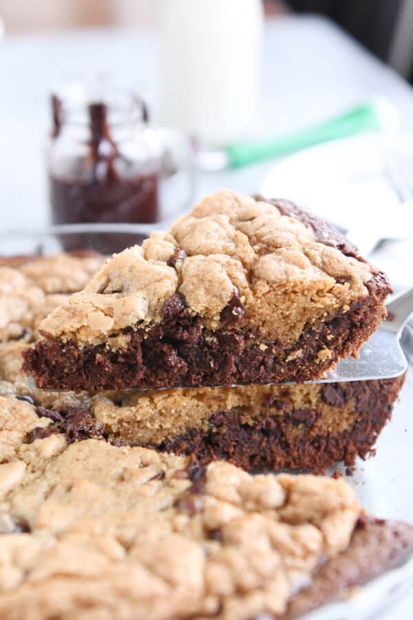 Lifting piece of brookie pie out of pie dish with pie server.