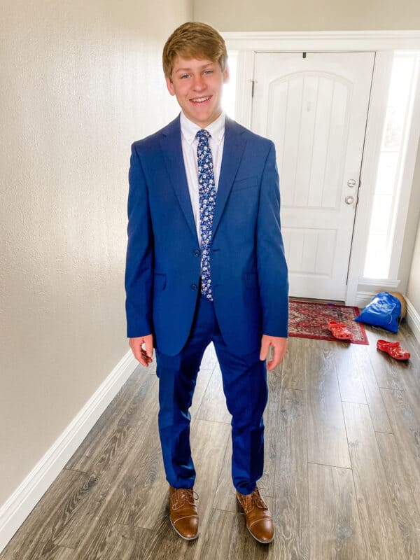 teenager in blue suit next to wall