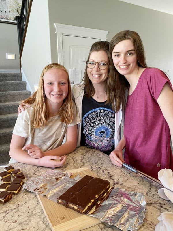 three woman standing in front of a pan of nanaimo bars