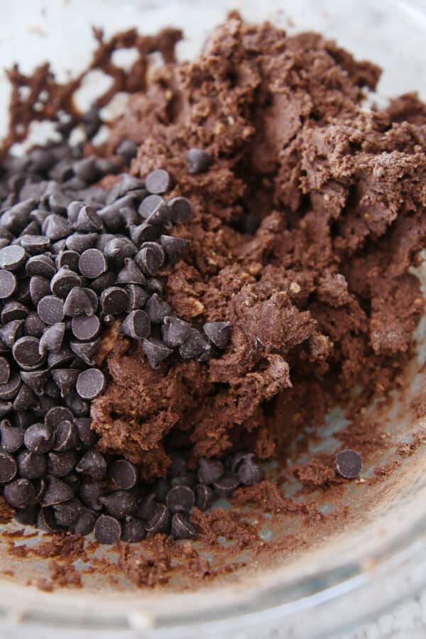 Chocolate cookie dough with chocolate chips in glass bowl.