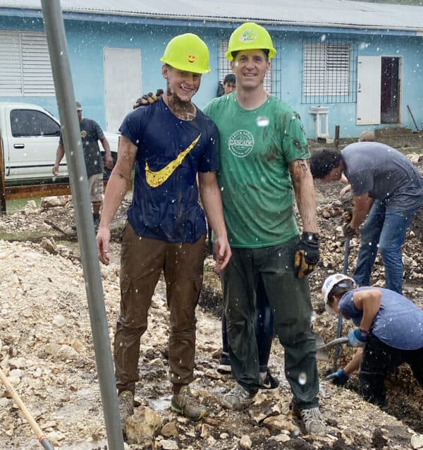 father and son in hard hats standing in rain