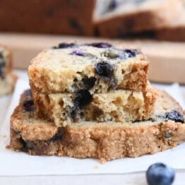 loaf of blueberry muffin bread split in half on top of full slice of bread