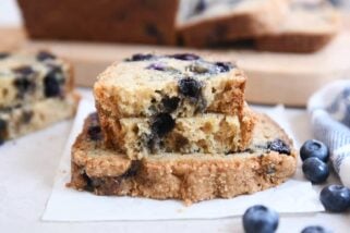 loaf of blueberry muffin bread split in half on top of full slice of bread