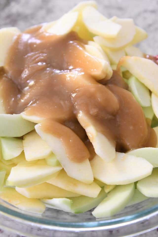Adding brown sugar sauce to sliced apples.
