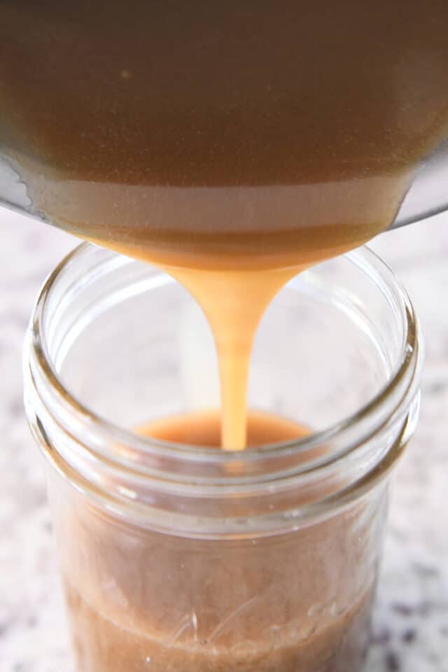 Pouring butterscotch sauce into jar.
