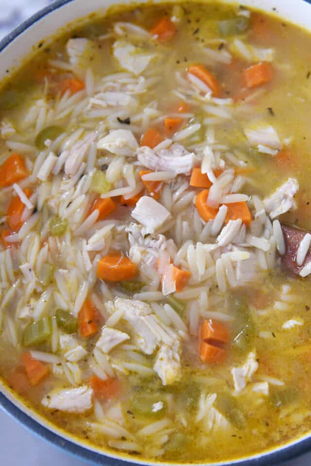 Cast iron pot filled with lemon chicken orzo soup.