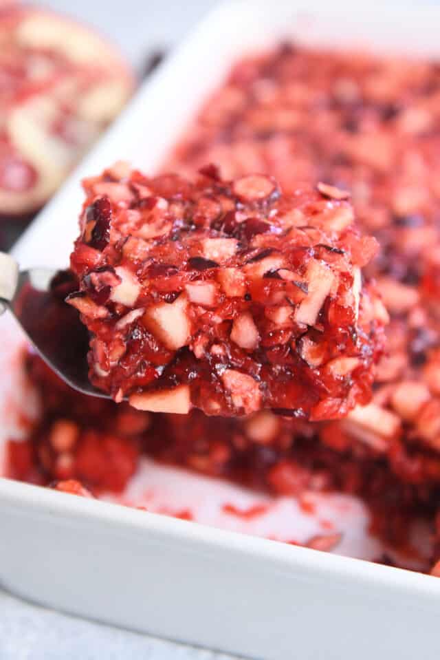 Square of cranberry pomegranate jello salad on metal spatula.