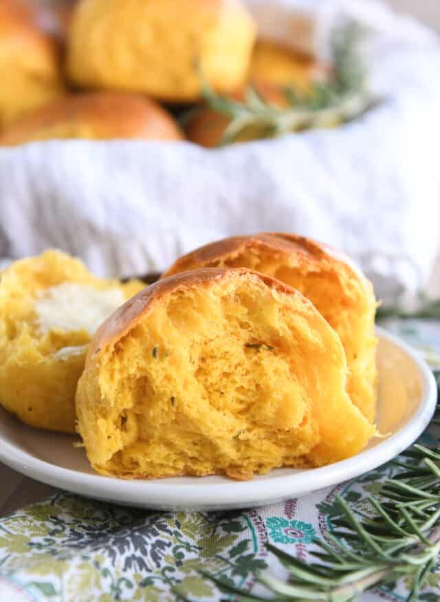 Pumpkin dinner roll in half on white plate.