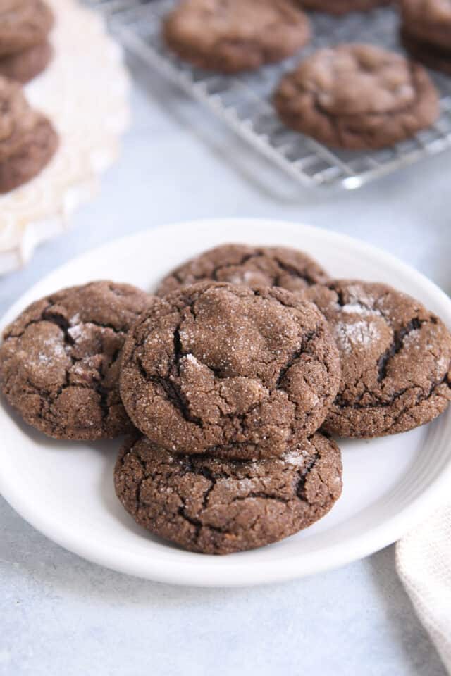 Five chewy chocolate ginger molasses cookies on white plate.