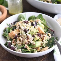 serving of kale and wild rice salad in white bowl with fork