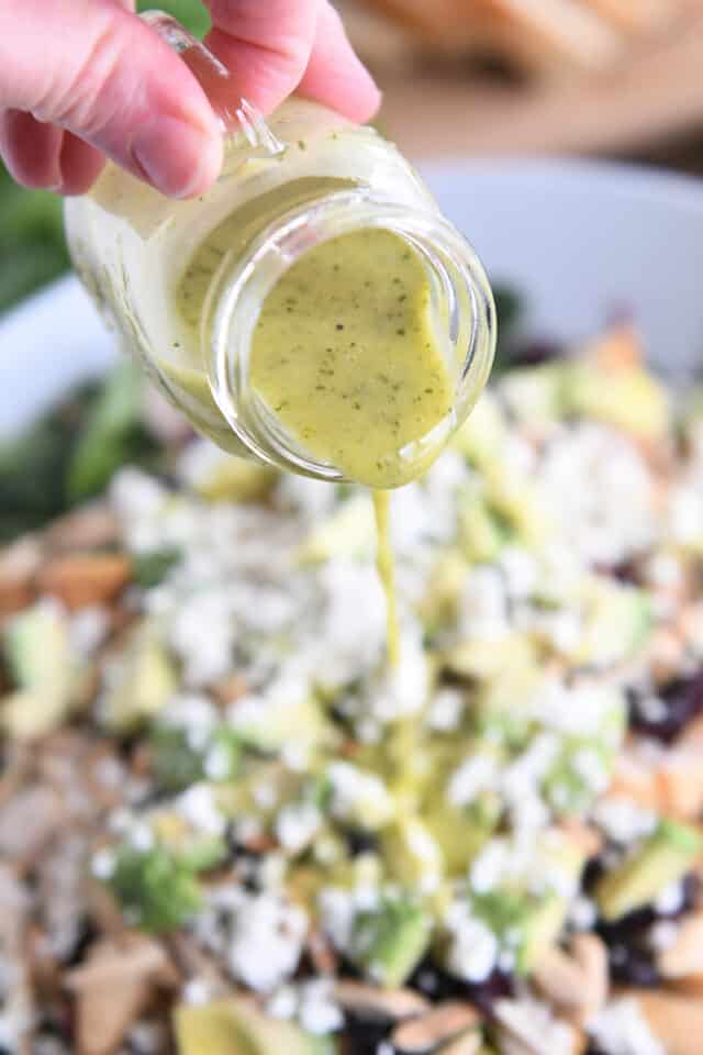 Pouring cilantro dressing over kale and wild rice salad.