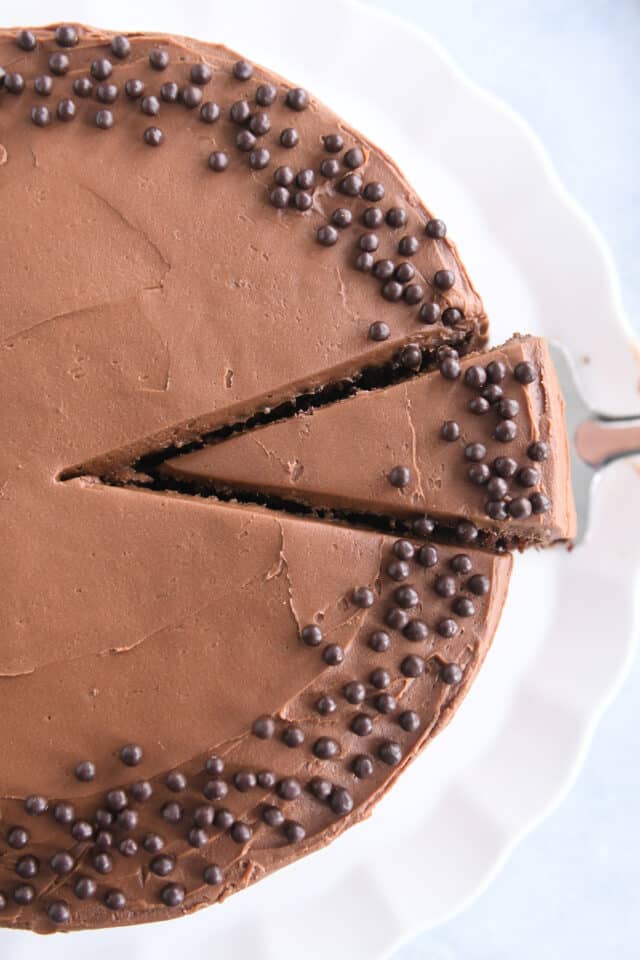 Top down view of frosted chocolate cake with piece sliced.