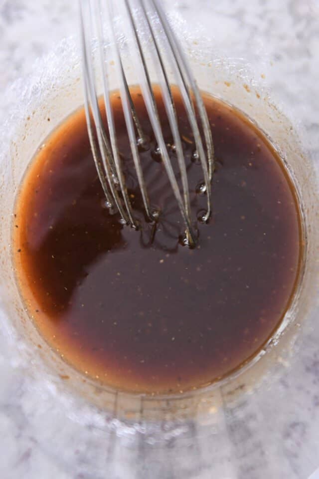 Marinade for pork chops in liquid measuring cup with whisk.