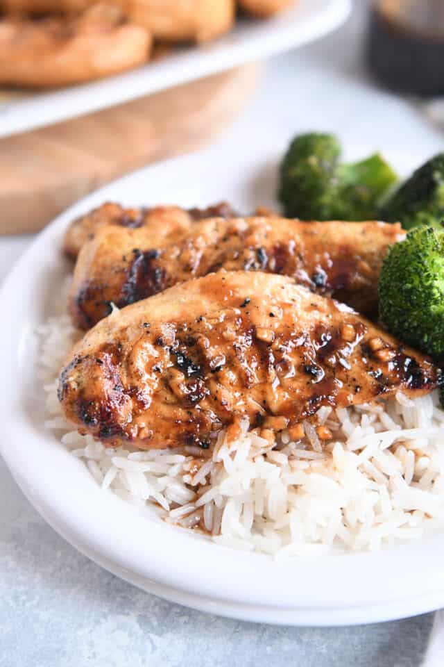 Two spiced ginger lime chicken tenders on bed of white rice on white plate.