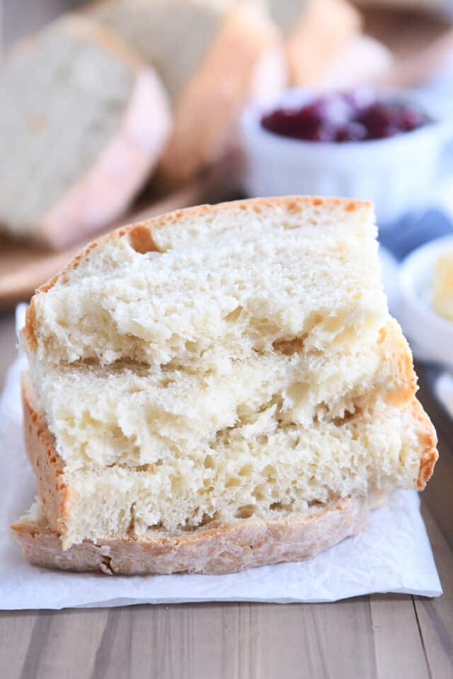 Four slices of sourdough peasant bread stacked on white parchment paper.