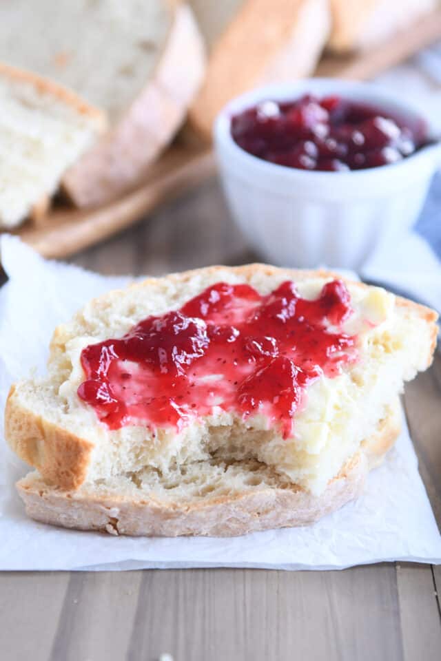 Two slices of sourdough peasant bread stacked with jam and butter on top slice.