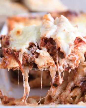 scooping serving of easy cheesy weeknight pasta bake out of white 9X13-inch pan
