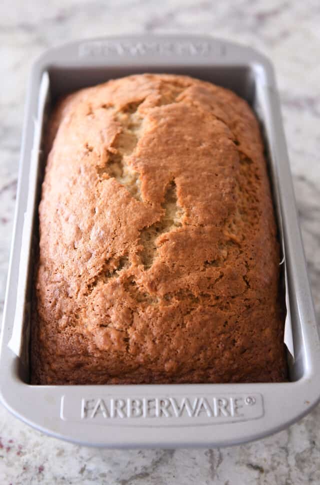 Loaf of baked banana bread in loaf pan.
