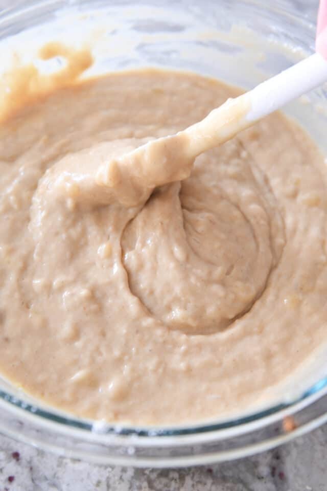 Banana bread batter in glass bowl with rubber spatula.
