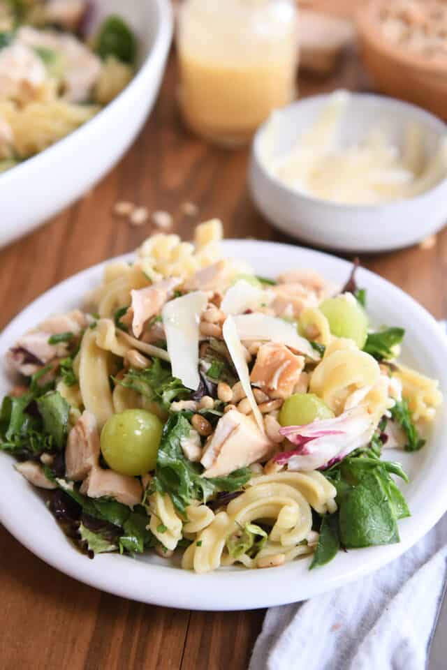 Serving of vineyard chicken and pasta salad on small white plate.