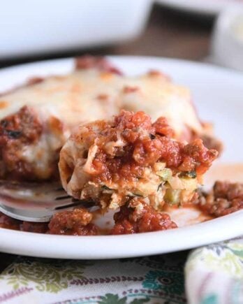 fork scooping bite of zucchini casserole on white plate