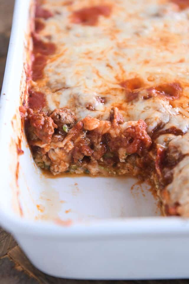 Cheesy zucchini spaghetti casserole in white baking dish with serving taken out.