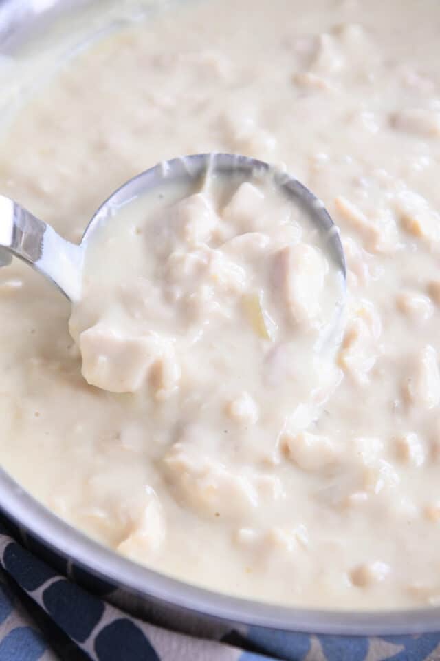 Ladle scooping up portion of white chicken gravy.