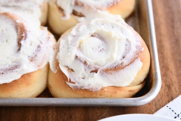baked cinnamon rolls with frosting on sheet pan