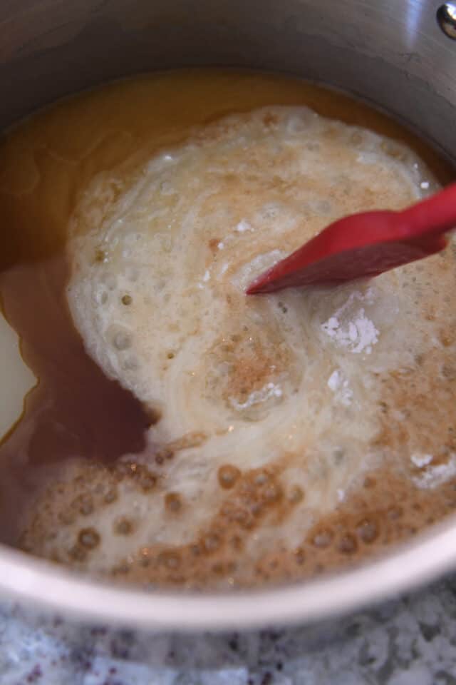 Stirring vanilla and baking soda into syrup in saucepan.