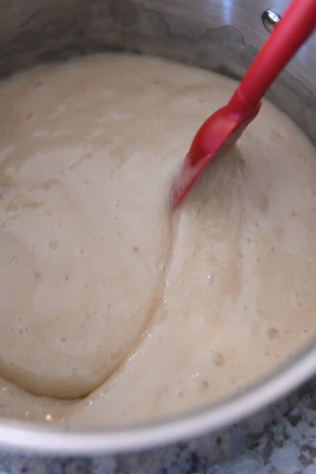 Stirring syrup in saucepan with red spatula.