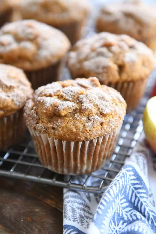 Several baked muffins on cooling rack with blue and white towel.