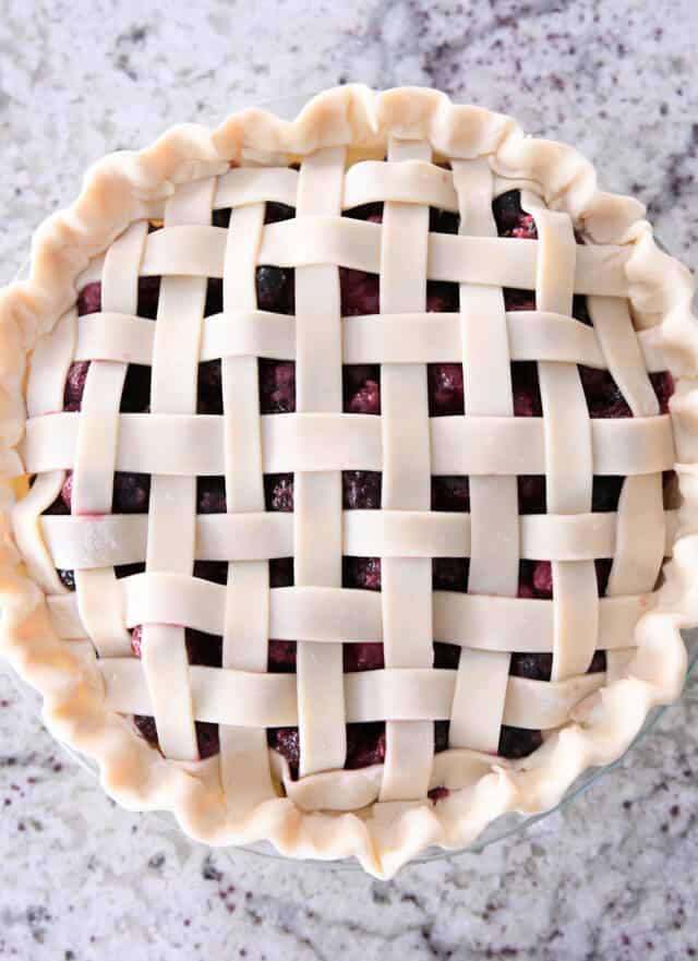 Unbaked triple berry pie with fluted edges.