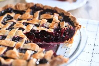 Triple berry pie in glass pie dish with one piece removed.