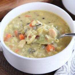 White bowl with spoon scooping up chicken and wild rice soup.