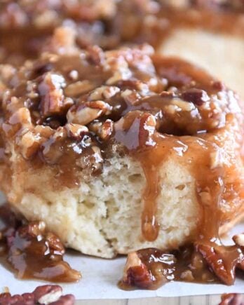 Caramel pecan sticky bun with pecans on edges on parchment paper.