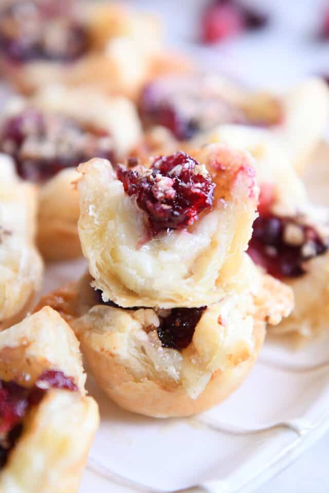 Cranberry brie bite bit in half stacked on top of another puff pastry bite.