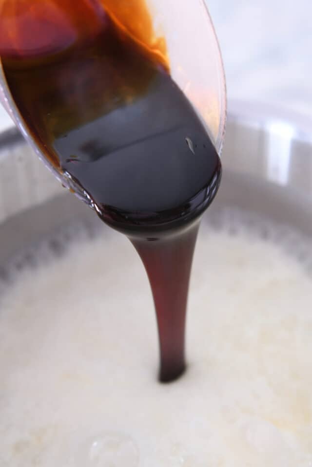 Pouring molasses into sugar mixture in pan.