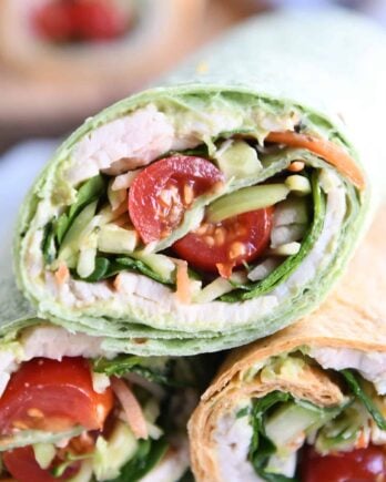 Half of a turkey avocado veggie wrap stacked on two other wraps.