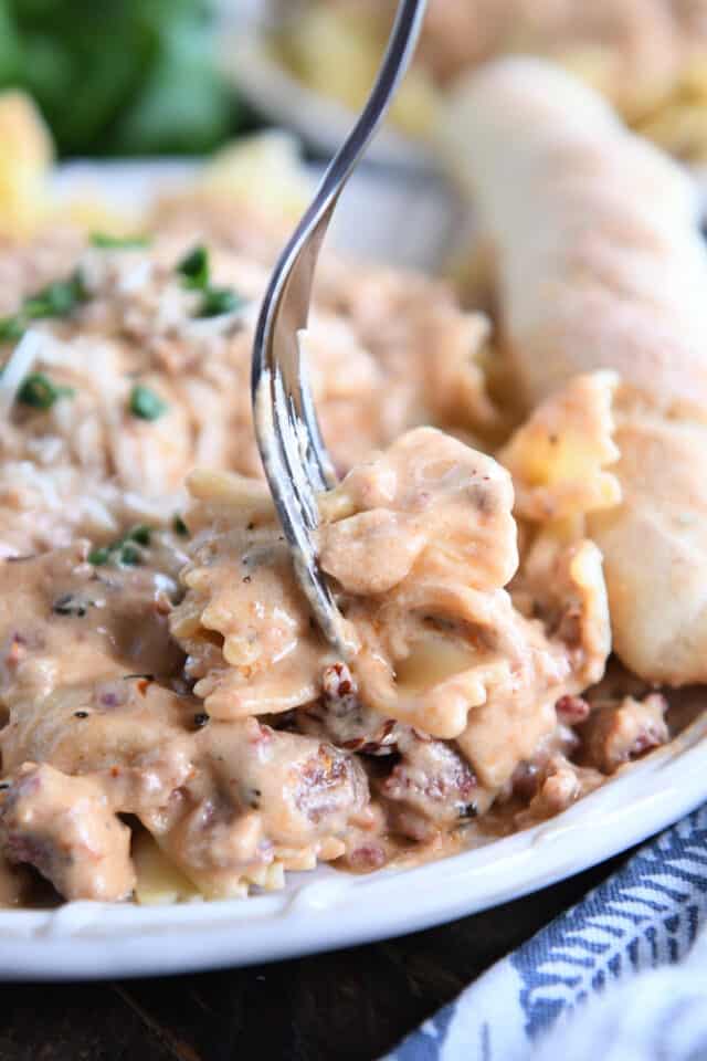 Fork spearing several bowtie pasta pieces with creamy pasta sauce.