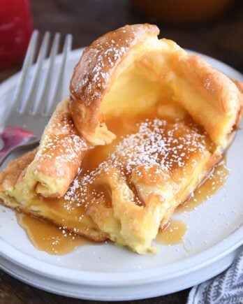 Square of golden German pancake on white plate.