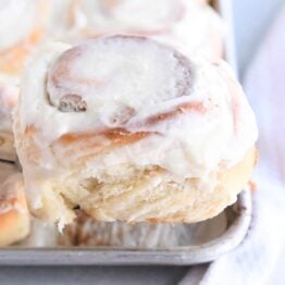 Frosted cinnamon roll on spatula.