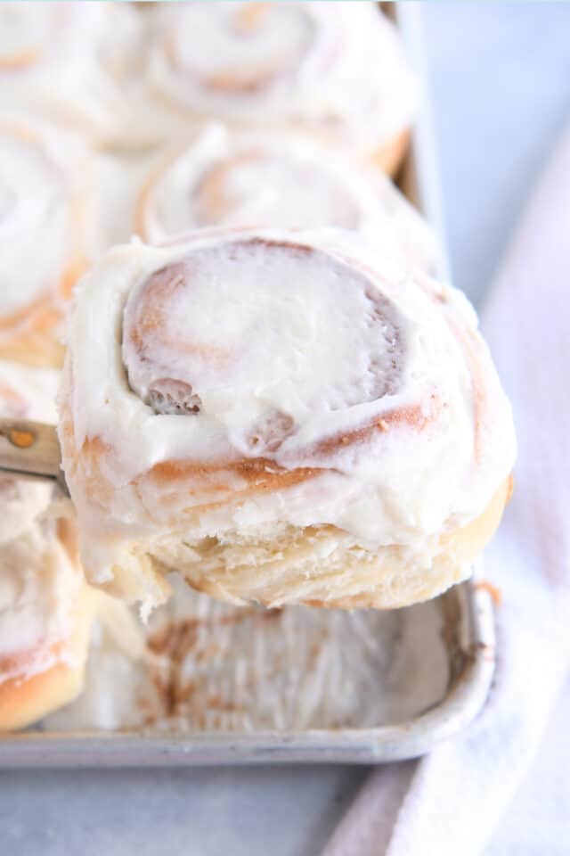 Frosted cinnamon roll on spatula.