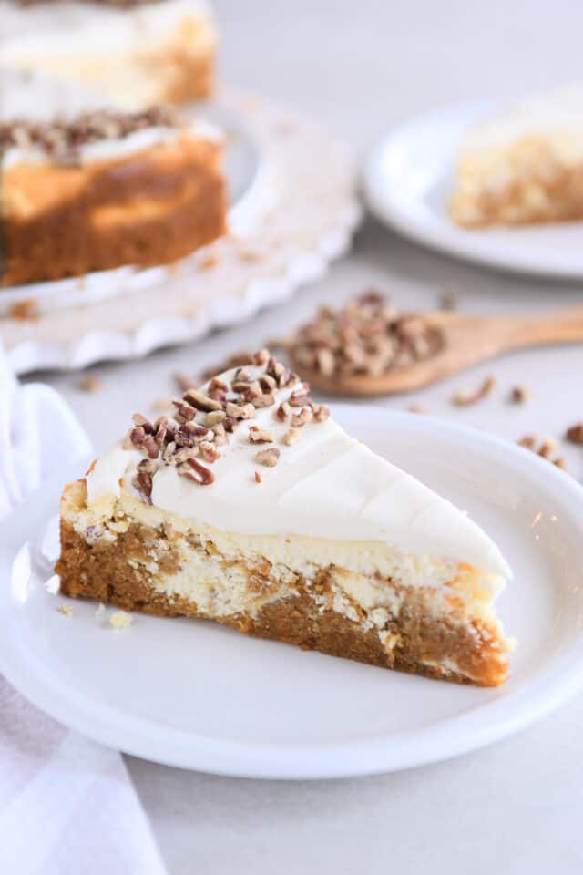 Slice of carrot cake cheesecake on white plate.
