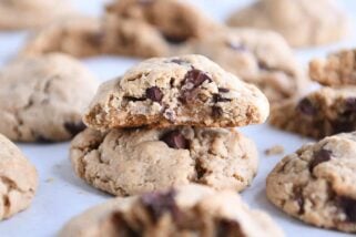 Half cookie stacked on top of whole cookie on parchment lined baking sheet.