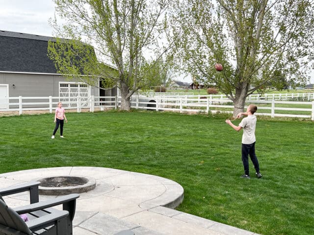 Two kids playing football in back yard