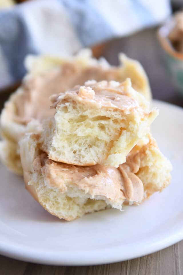 Fluffy roll split in pieces on white plate.