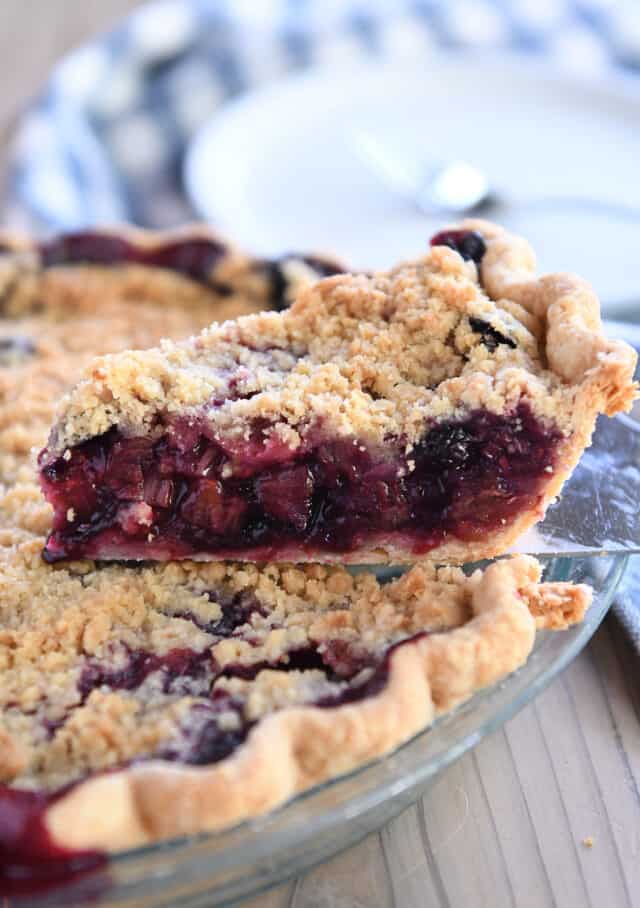 Slice of berry rhubarb pie on pie server.