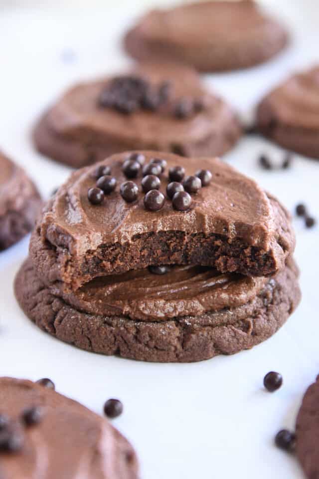 Half of chocolate cookie stacked on another cookie on white parchment paper.