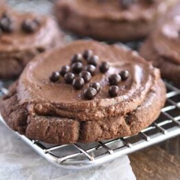 Frosted chocolate sugar cookie with chocolate pearls on metal rack.