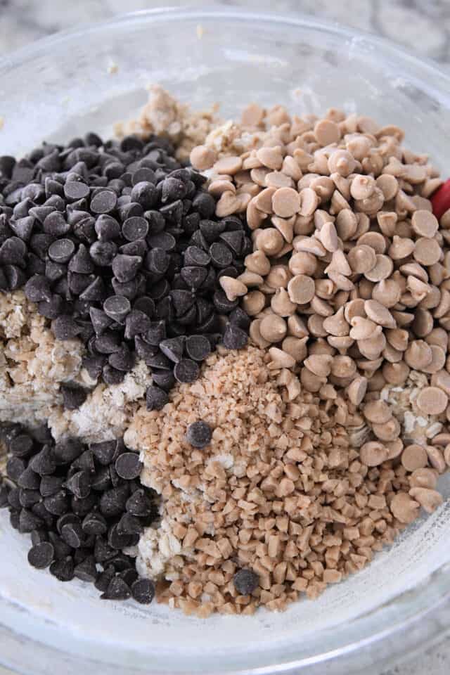 Glass bowl with cookie dough, chocolate chips, peanut butter chips and toffee bits.